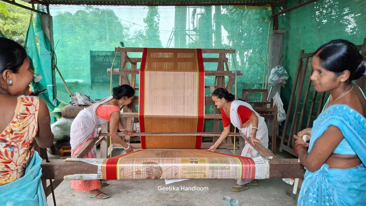 Close-up of hands working with Assamese textile materials