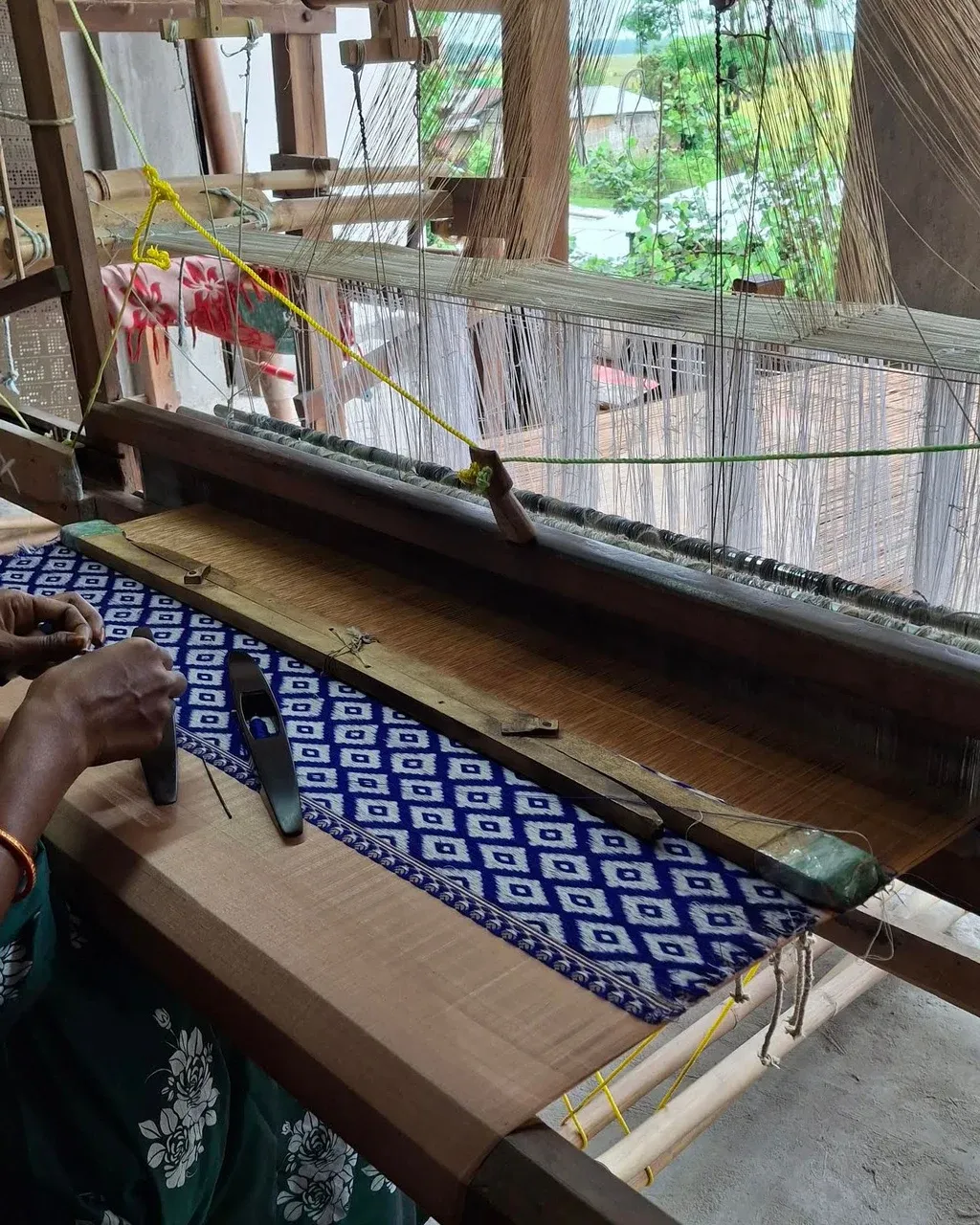 Hands working with Assamese textile materials